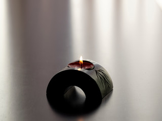 Close-up of small single red candle shining in a wood holder. Concept of self isolation, concept of...