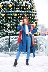 Portrait of young girl in blue jeans walking in a winter park