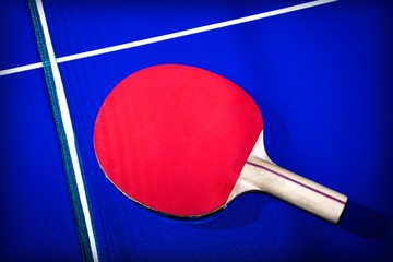 Red table tennis racket on blue table background