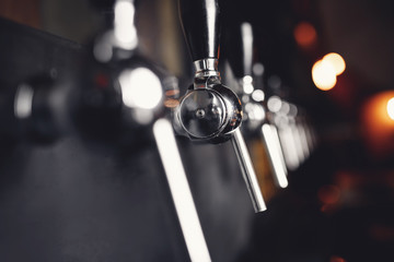 Beer craft steel taps raw in pub. Selective focus, dark background