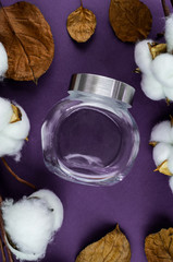 Fototapeta na wymiar Glass jar for food on a background of cotton and purple table