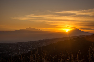Sol saliendo detr&aacute;s de los volcanes