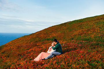 happy couple in love sit on the grass in the arms of each other.