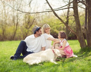 Fototapeta premium Family sitting in park with dog