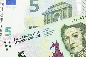 A five peso bill from Argentina, close up in macro with a red, five Euro European bank note