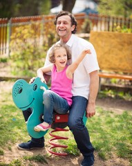 Father and daughter on playground spring rider