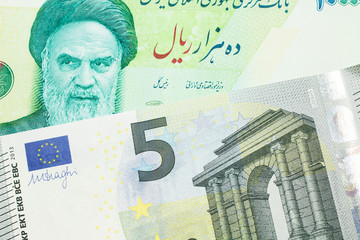 A close up image of a green Iranian ten thousand rial bank note with a blue and green five euro note from France in macro