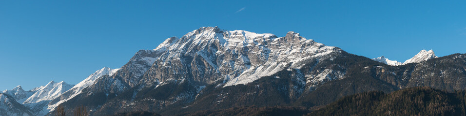 Fototapeta premium Panoramic view of snowy alpine mountain range on a clear blue day during winter in Innbruck Austria Tyrol