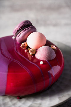 Close up view on a pink purple cheese cake decorated by macaroons and