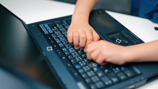 Angry boy breaks laptop keyboard with his hands.
