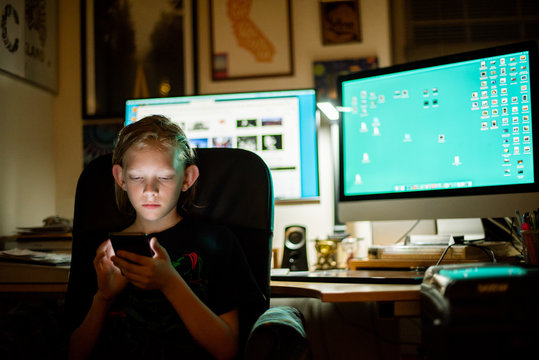 Kid sitting at desk using smart phone
