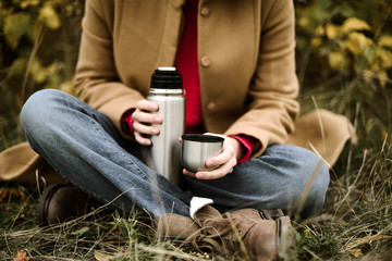 Young woman  pouring tea from thermos flask into cup