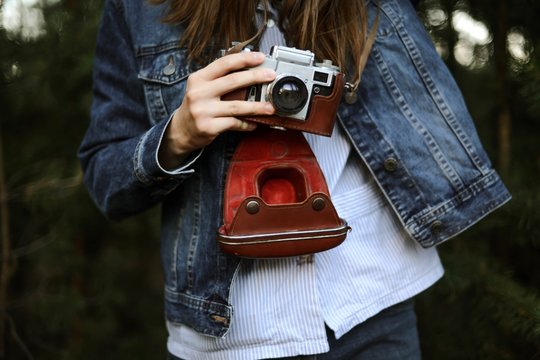 Woman with camera while standing against pine trees