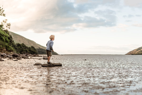 Little kid standing on a rock in a mudflat