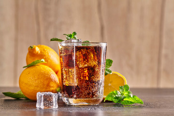 Fresh made Cola, mint and lemon on wooden background. Close up.
