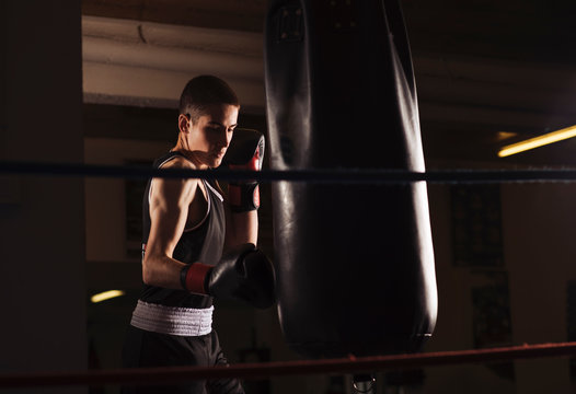 Young man boxer practicing a hit boxing during workout.