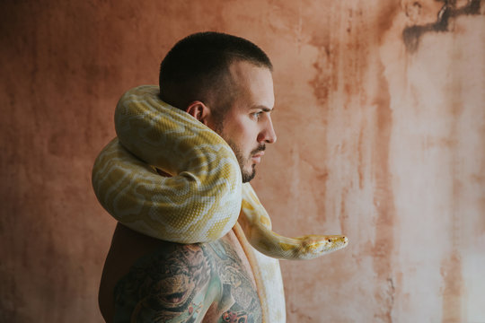 Side view of man with python circling his neck