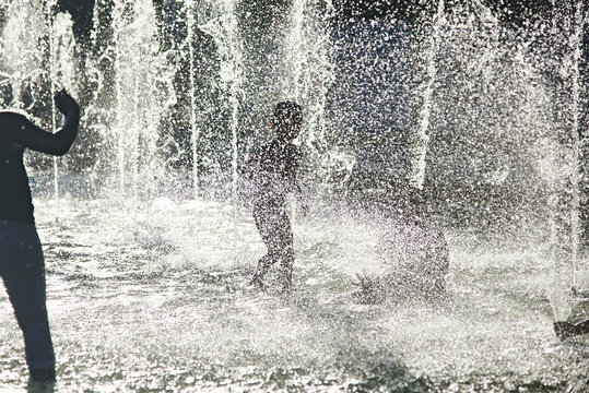 Silhouette of kids cooling down in a fountain during heatwave