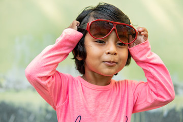 Cute little girl wearing fashionable sunglasses and making fun