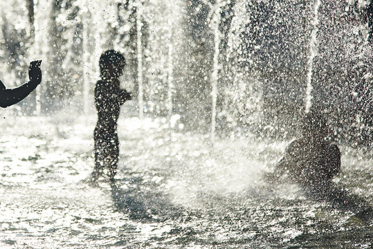 Silhouette of kids cooling down in a fountain during heatwave