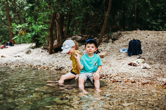 Young boy and girl sitting on rock in water near Barton Springs