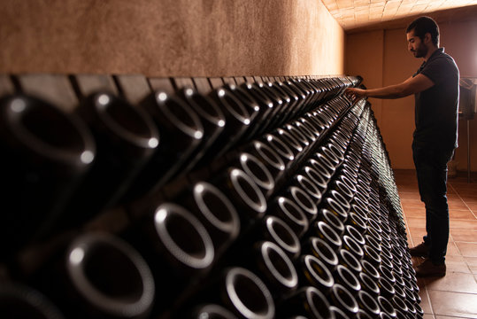 Attentive cellar worker arranging bottles of champagne