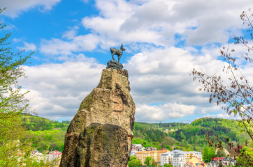 Chamois Statue Socha Kamzika at Deer Jump Jeleni Skok Lookout with Karlovy Vary (Carlsbad) colorful beautiful buildings and Slavkov Forest hills background, West Bohemia, Czech Republic © Aliaksandr