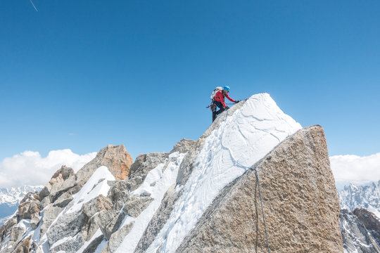 Alpinist in red shirt high up on a mixed terrain alpine ridge