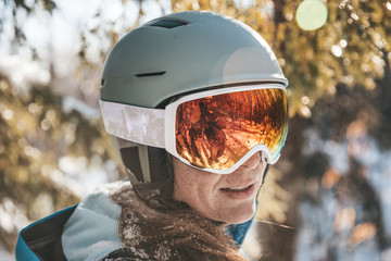 Woman in ski goggles and helmet in backlit snow scene in New Hampshire