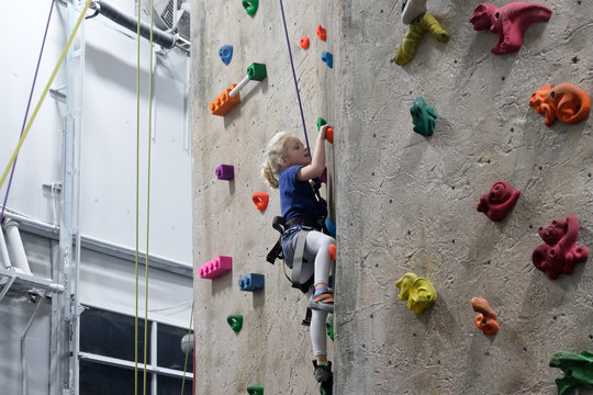 young girl climbing rock wall at indoor rock  climbing gym