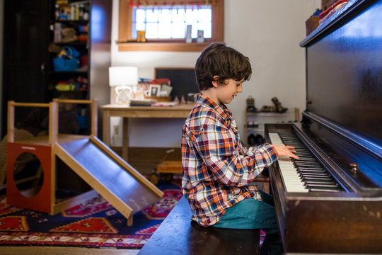 side view of a child sitting in window light practicing piano