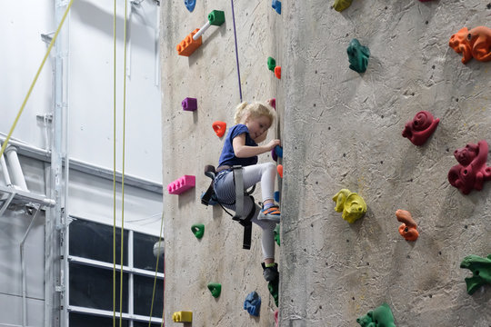 young girl climbing rock wall at indoor rock  climbing gym