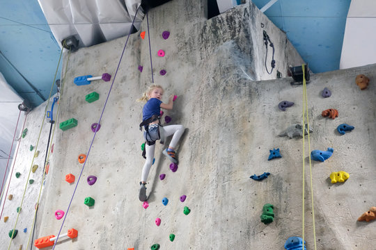 young girl climbing rock wall at indoor rock  climbing gym