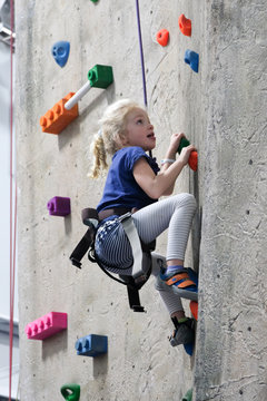 young girl climbing rock wall at indoor rock climbing gym