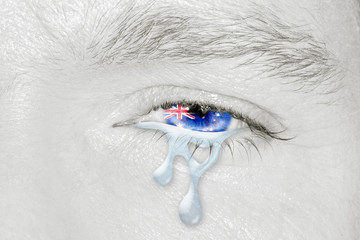 Crying eye with Australian Flag iris on black and white face. Concept of sadness and empathy for bushfire and natural disasters in Australia. Patriotic metaphor.
