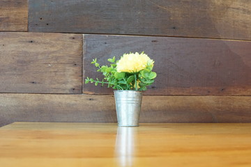 Yellow flowers with green leaves in an aluminum flower pot.
