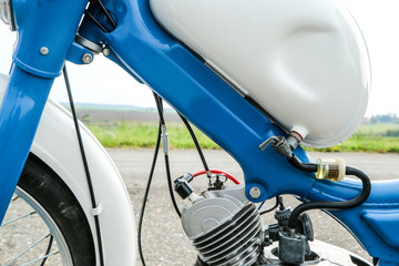 The detail of the old light motorcycle or moped with part of the engine, fuel tank and fuel lead.  