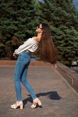 Pretty stylish brunette girl in blue jeans and white blouse
