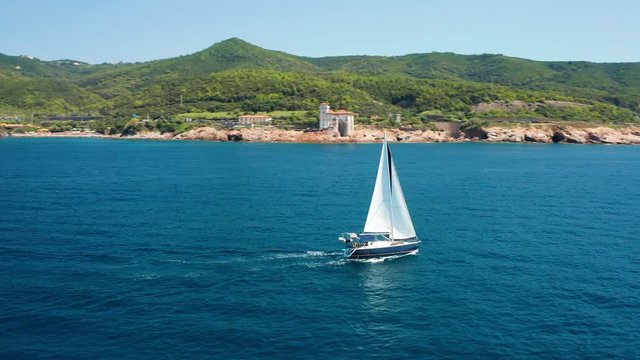 Aerial pan around yacht on Etruscan coast, Boccale Castle in the distance 