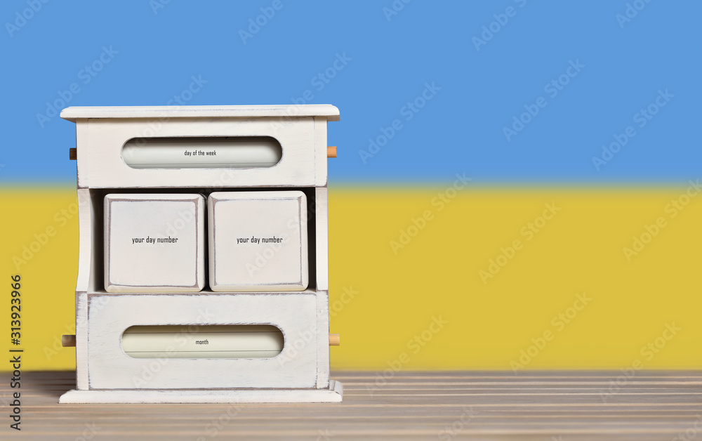 Fototapete wooden retro calendar with free space for a date on the background of the flag of ukraine. template 