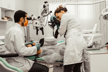 Naklejka na ściany i meble Two dentists treat a patient. Professional uniform and equipment of a dentist. Healthcare Equipping a doctor’s workplace. Dentistry