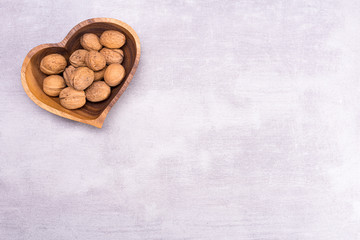 Walnut on a plate in the shape of a heart on a gray background with a place for text, top view, flat lay