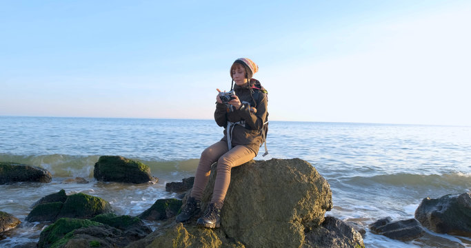 Young female travelr with backpack and retro film camera travel in the autumn mountains near sea	