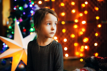 Little girl girl with a gift, cozy warm winter evening at home lies on the floor with gifts