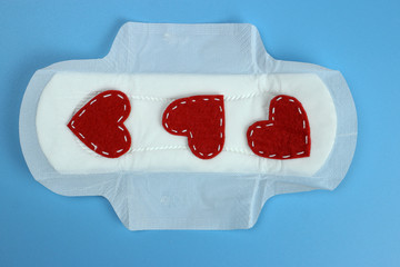 Sanitary pad With red hearts on blue. Personal hygiene, the concept of feminine hygiene. Critical days, blood period, menstrual cycle.