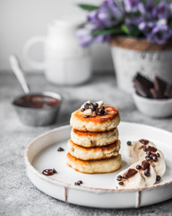 Fried curd pancakes. Cheesecakes with banana and chocolate are beautifully served. The concept of wholesome homemade food. Table decor.