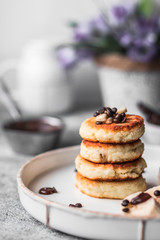 Fried curd pancakes. Cheesecakes served with banana and chocolate. The concept of wholesome homemade food. Close-up, light background.