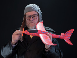 Portrait of strange elderly man has red airplane in his hands and torque spinner of apropeller....
