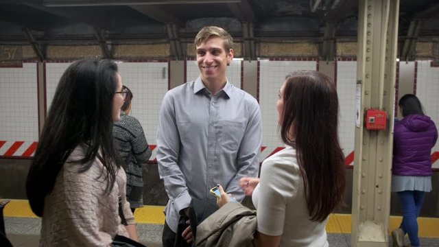 Three attractive young people wait for the subway train to arrive in New York City. They are laughing and enjoying life.