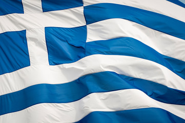 Abstract close-up of a giant flag of Greece waving outdoors in bright Mediterranean sun